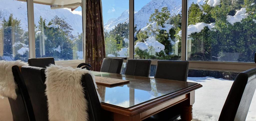 a dining room with a table and chairs and windows at Aoraki Alpine Chalet in Mount Cook Village