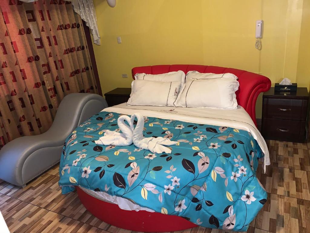 a bed with a blue comforter with two swans on it at Hotel Manantial No,001 in Lima