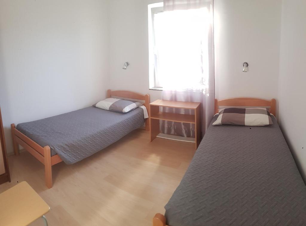 Cette petite chambre comprend 2 lits et une fenêtre. dans l'établissement Apartment Anita, à Fažana