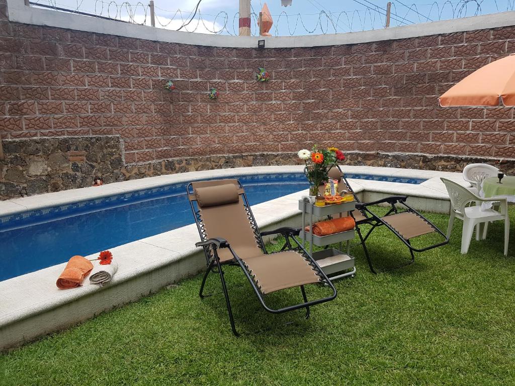 twee stoelen en een tafel naast een zwembad bij Casa los Peregrina in Cuernavaca