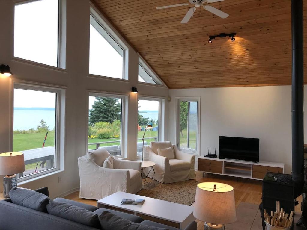 a living room with a couch and chairs and windows at Private Waterfront Luxury on the Bras D'Or Lake in Sydney Forks
