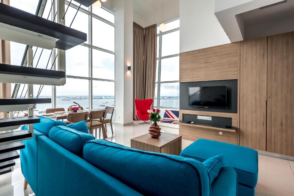 sala de estar con sofá azul y TV en Maritime Luxury Suite By J&K Homestay, en George Town