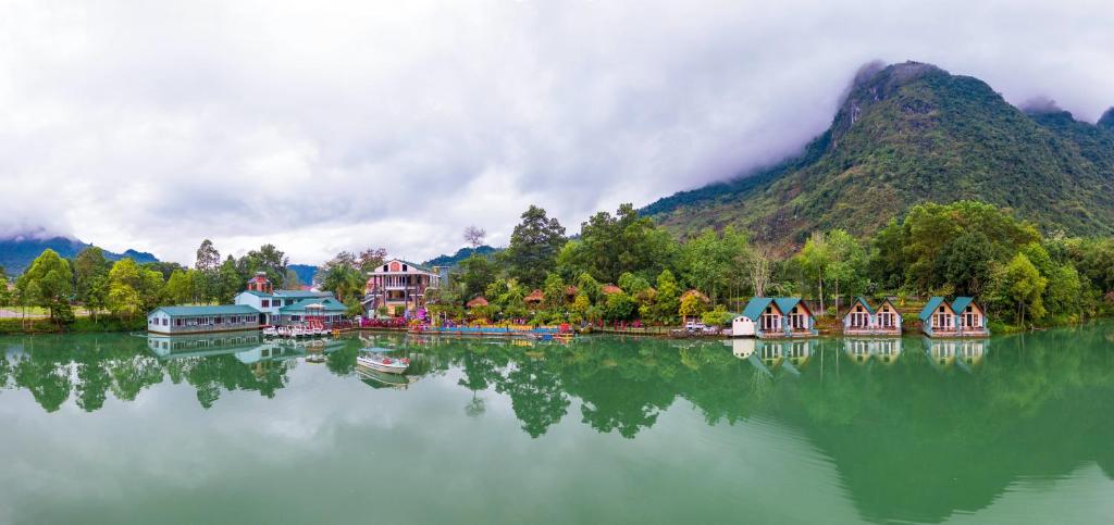a group of houses on the water near a mountain at Truong Xuan Resort in Ha Giang