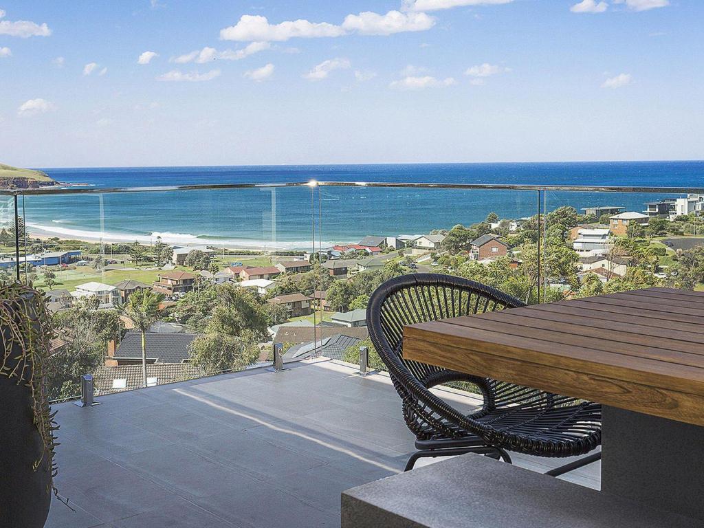 a balcony with a table and a view of the ocean at Cosmopolitan at SoHo in Gerringong