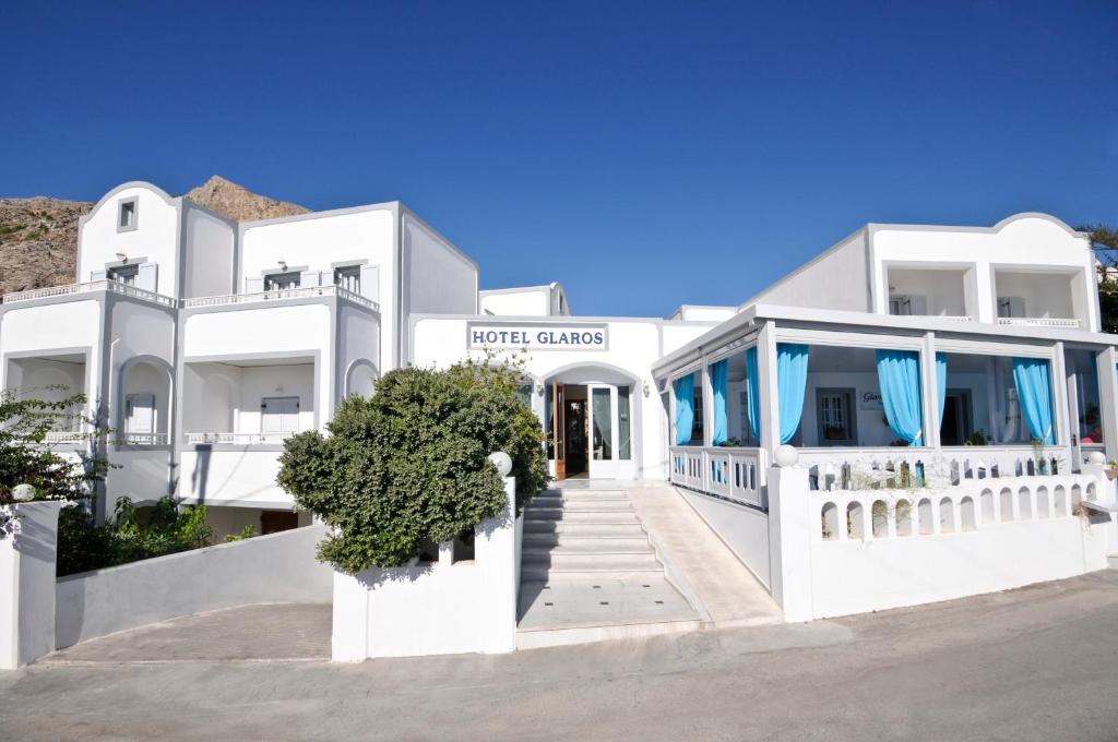a white building with blue curtains in front of it at Glaros Hotel in Kamari