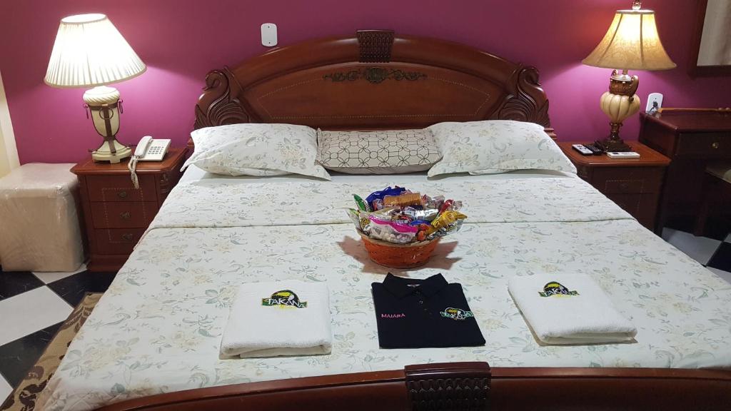 a bed with two napkins and a basket of flowers on it at Hotel Takana in Tabatinga