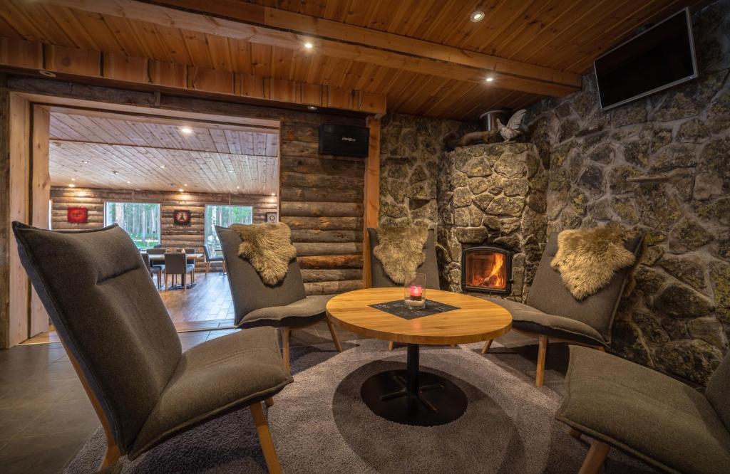 a living room with a table and chairs and a fireplace at Wilderness Hotel Nellim & Igloos in Inari
