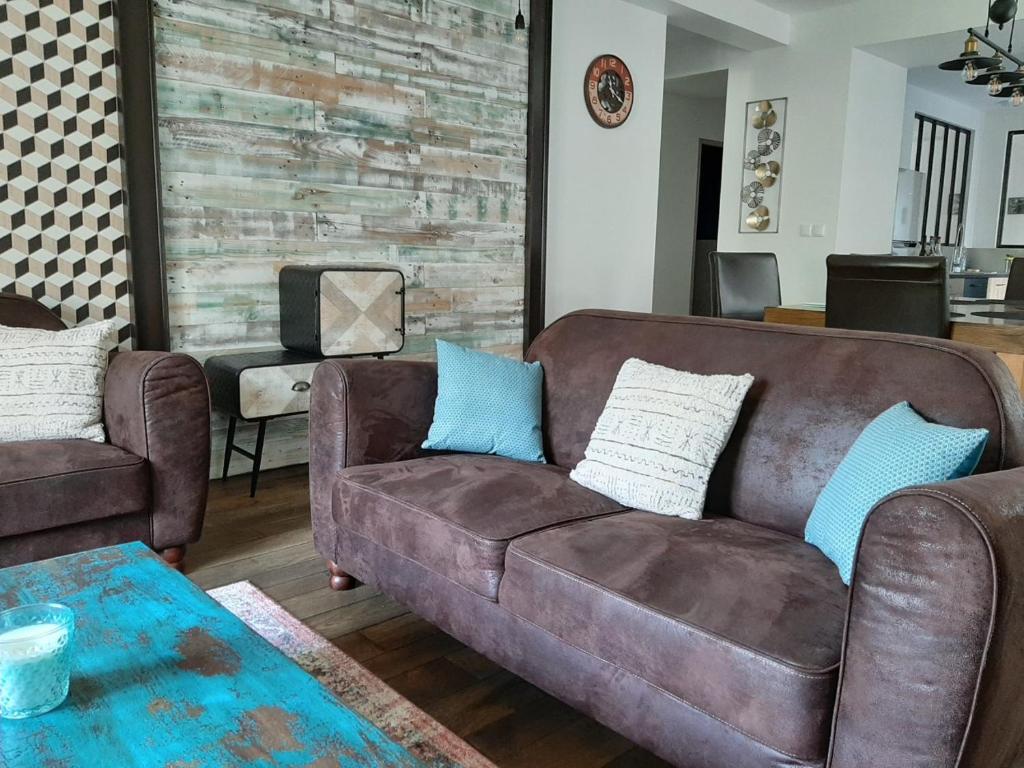 a living room with a brown couch and blue pillows at Le Manoir, appartement Onyx in Le Bourg-dʼOisans