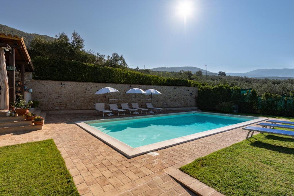una piscina in un cortile con sedie e ombrelloni di Agriturismo Monte Cologna a Foligno