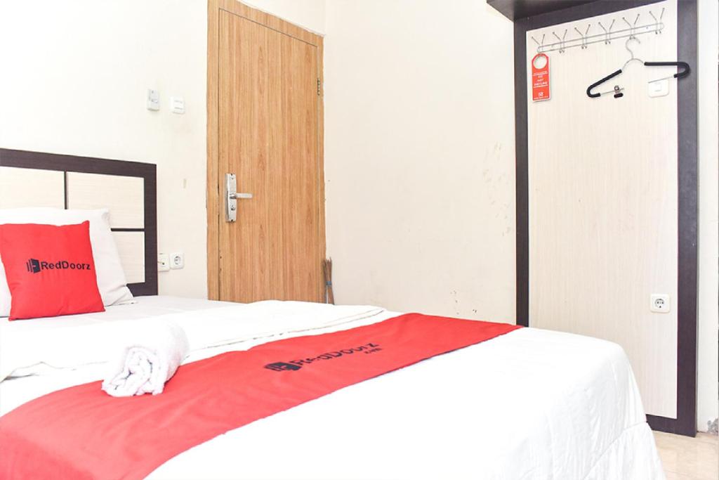 a bedroom with a bed with a red blanket at RedDoorz near Universitas Muhammadiyah Makassar in Makassar