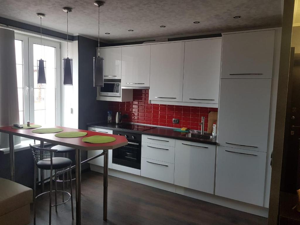 維堡的住宿－Krasnoflotskaya 4A，厨房配有白色橱柜和带凳子的桌子