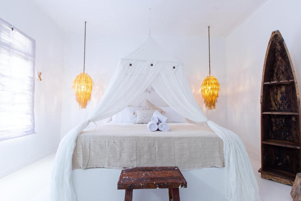 a bedroom with a white bed with a canopy at The Manik Toya in Uluwatu