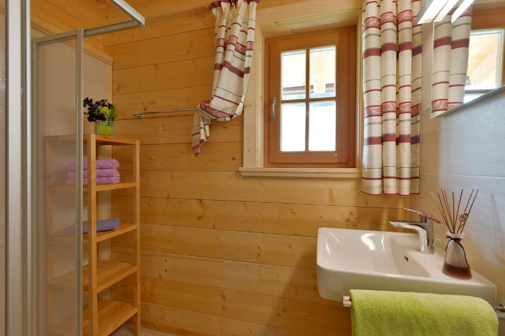ein Bad mit Holzwänden, einem Waschbecken und einem Fenster in der Unterkunft Ferienwohnung Lechenhof in Söll