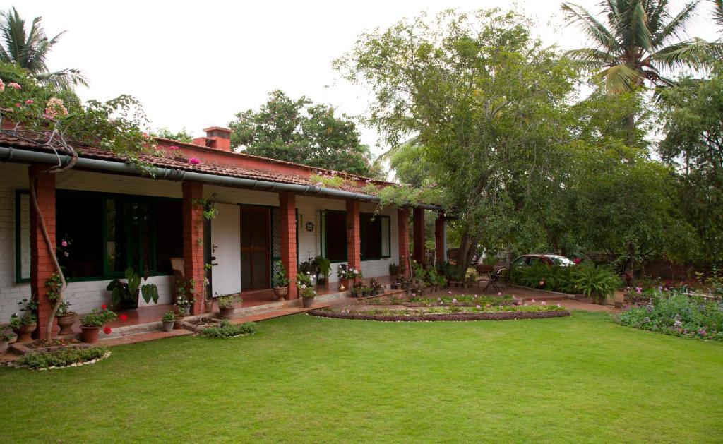 una casa con un césped verde delante de ella en Gitanjali Homestay, en Mysore