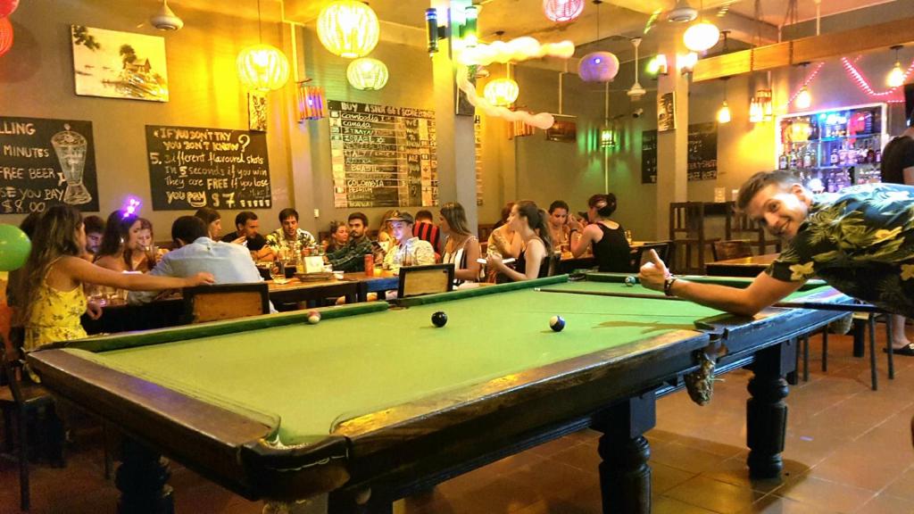a man standing in front of a pool table in a bar at Siem Reap Pub Hostel in Siem Reap