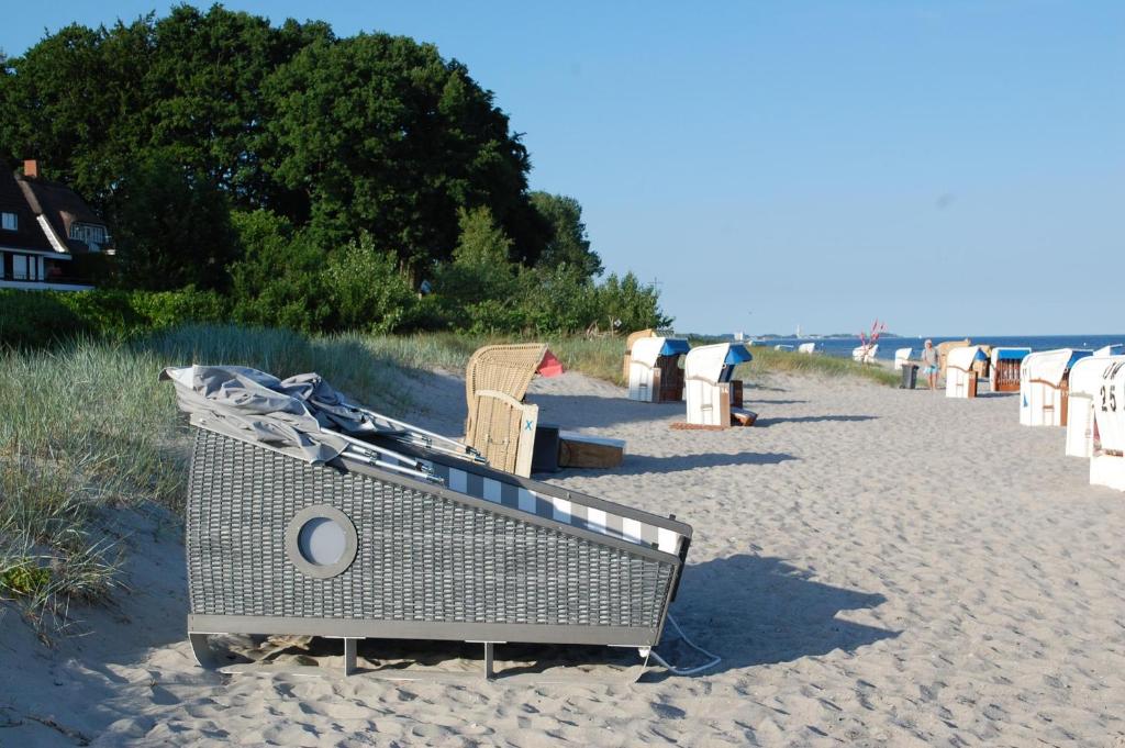 a beach with chairs and a boat on the sand at Schlafstrandkorb Nr. 1 in Sierksdorf