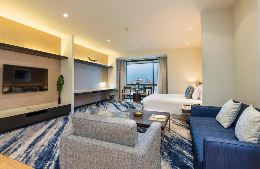 A large open-plan suite combining a bedroom, lounge, television wall and window-side dining area.