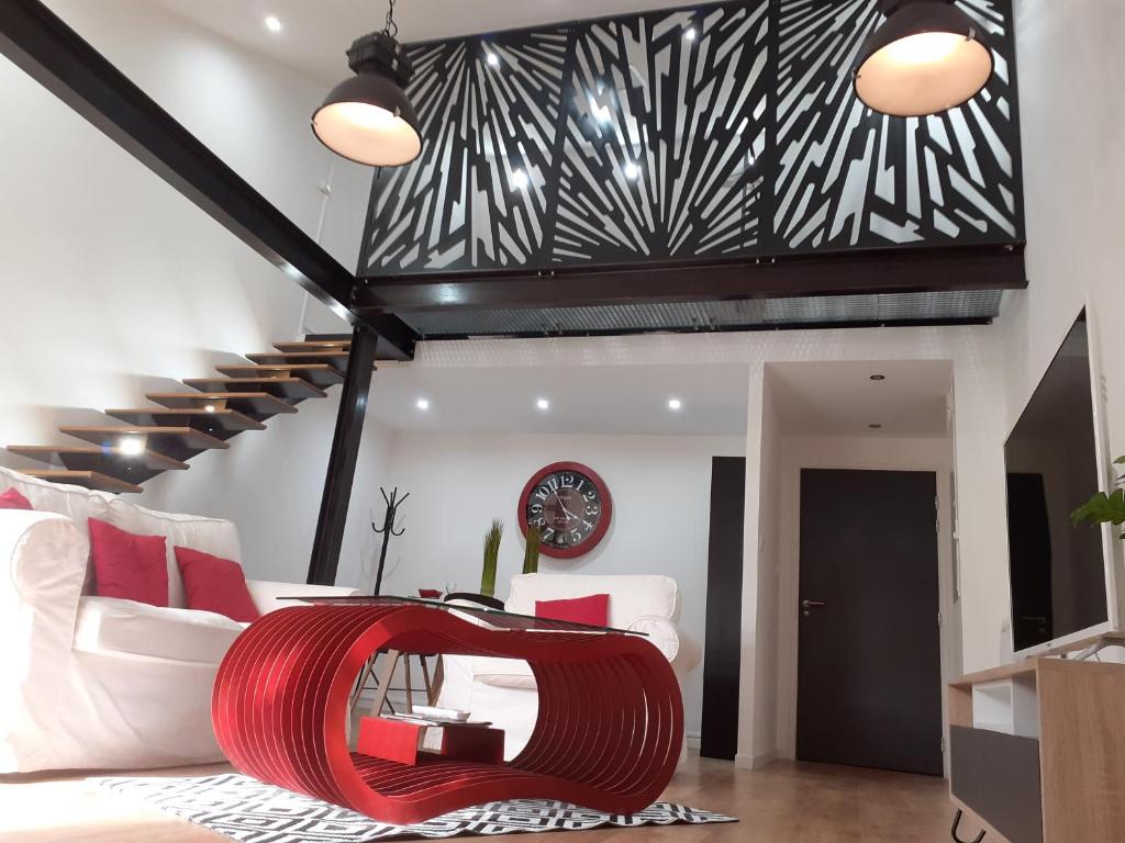 a living room with a red couch and stairs at " Les Lofts de Mérigonde " in Castres