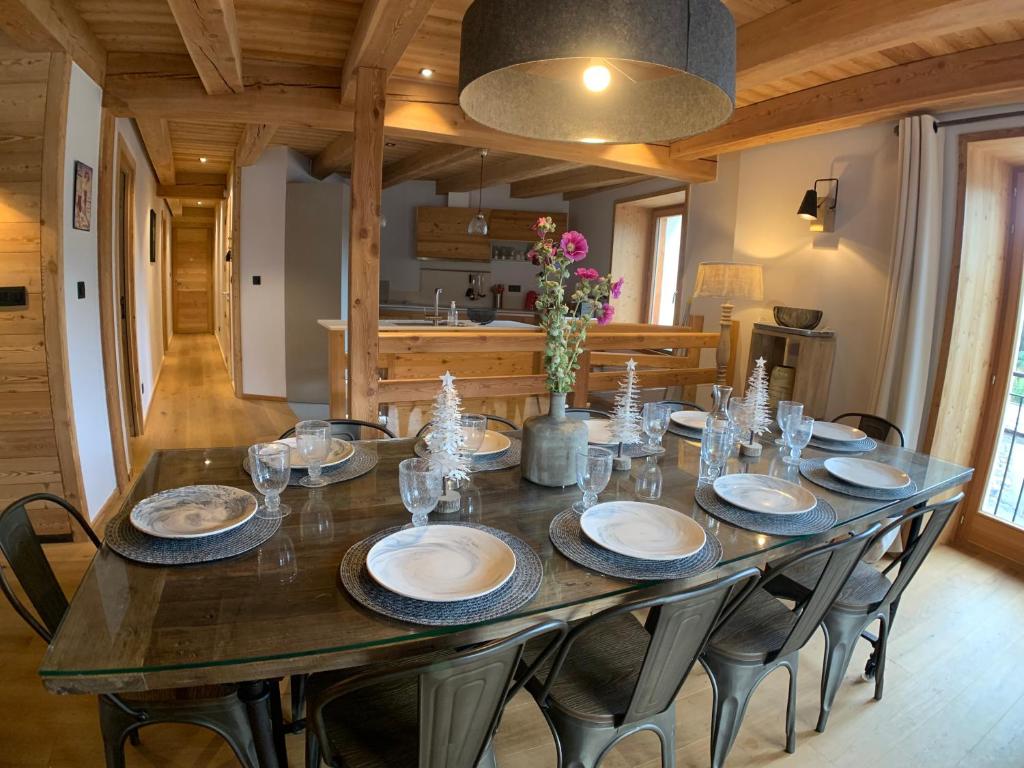 a large wooden table with chairs and plates on it at Le Gabion, luxueux appartement avec 10 couchages et sauna, Serre chevalier Vallée in Saint-Chaffrey
