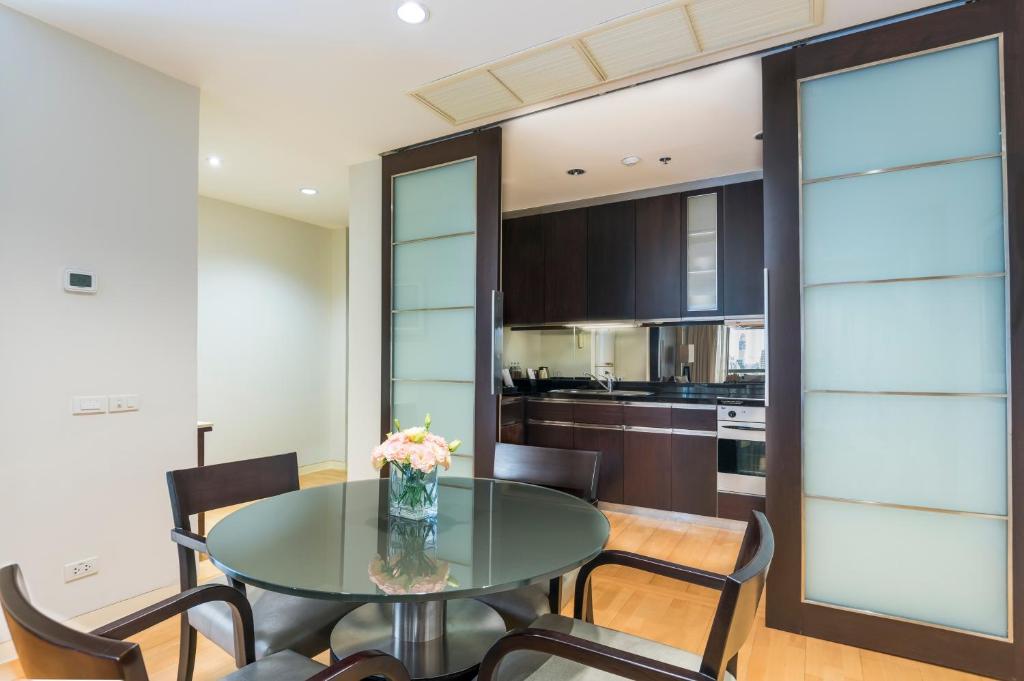 A dining area beside a compact fitted kitchen with dark cabinetry and an oven.