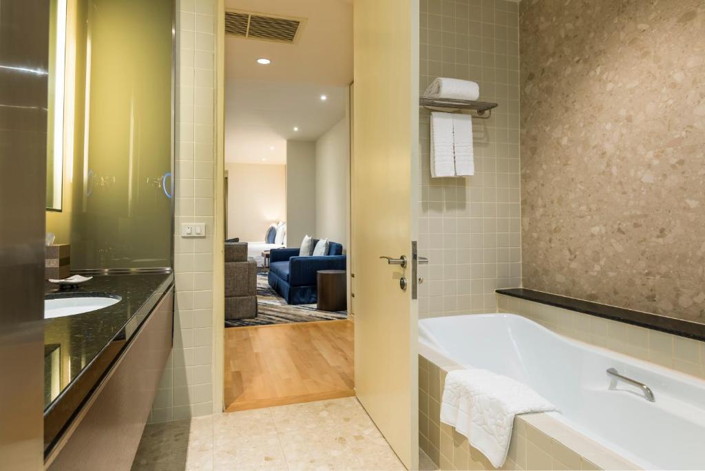 A bathroom with a full-length bathtub, vanity and a view toward the living area.