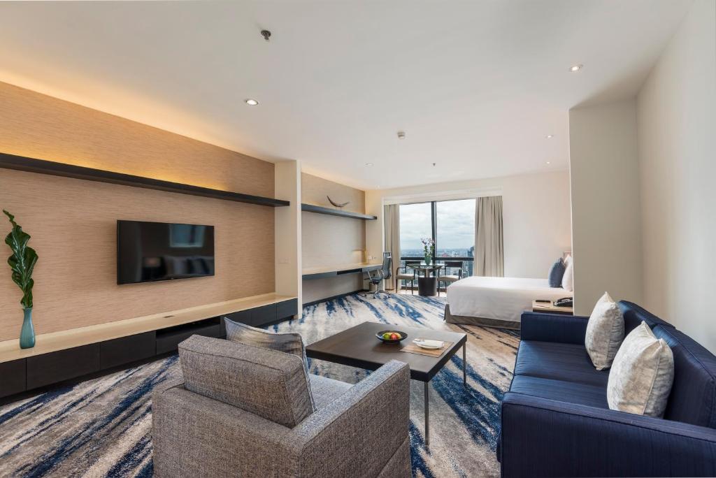 A spacious suite living area opening toward a bed and city-facing window.