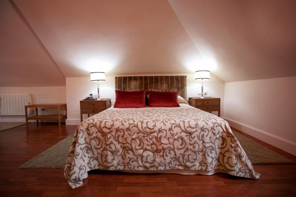 a bedroom with a large bed with red pillows at Hotel Hacienda Montenmedio in Vejer de la Frontera