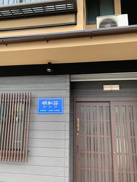 Una puerta a un edificio con un cartel. en 明和荘Mei Wa Inn en Kioto