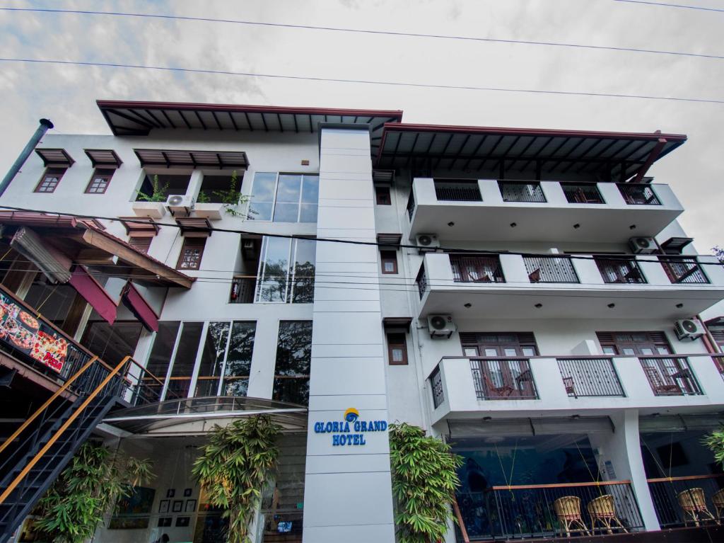 a tall white building with windows and plants at Gloria Grand Hotel in Unawatuna