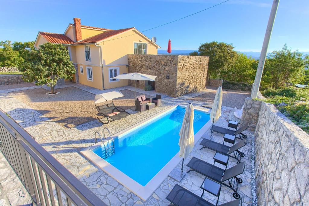 a swimming pool with chairs and a house at Villa Vrh in Krk