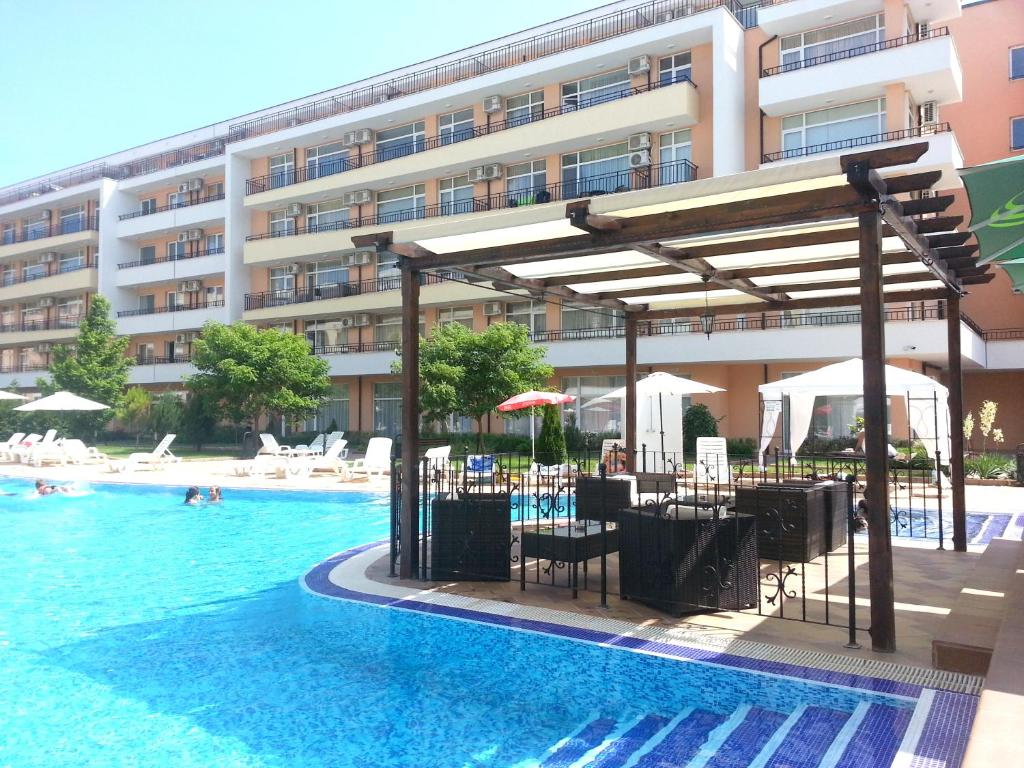 una piscina con mesas y sillas y un edificio en Menada Grand Kamelia Apartments, en Sunny Beach