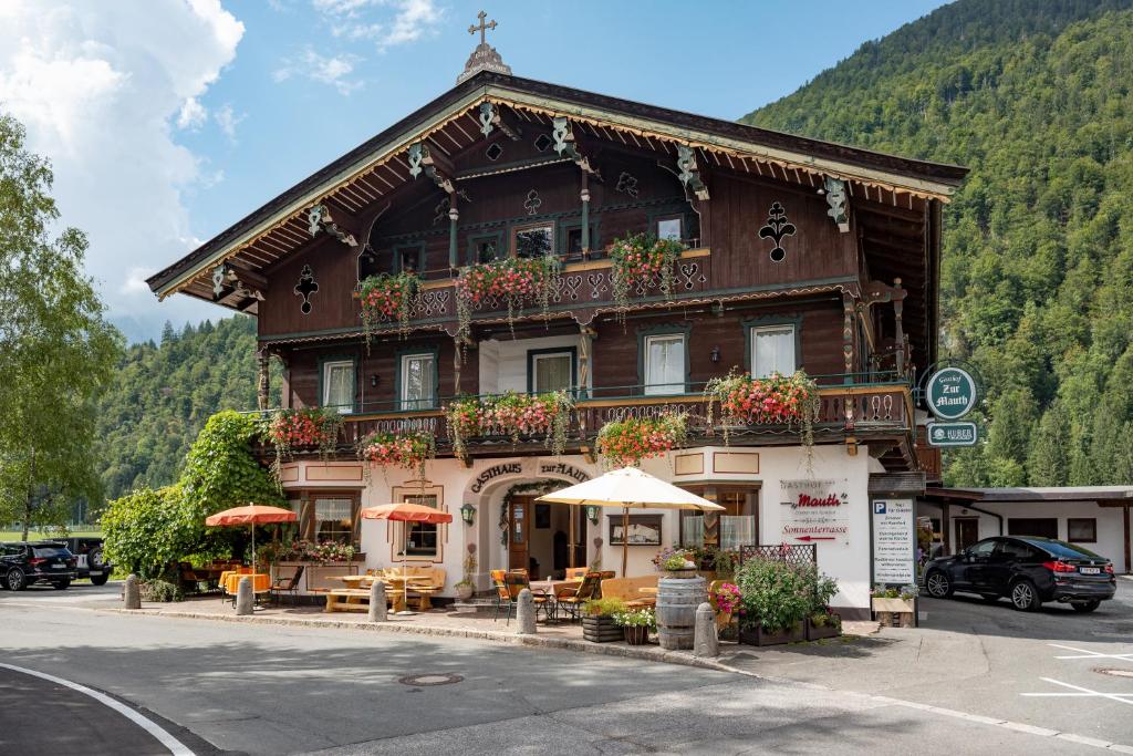 a building with tables and umbrellas in front of it at Landgasthof Mauth in Kirchdorf in Tirol