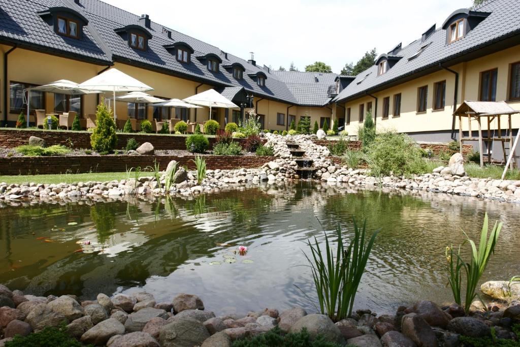 a hotel with a pond in front of a building at Hotel Paradiso in Suchedniów
