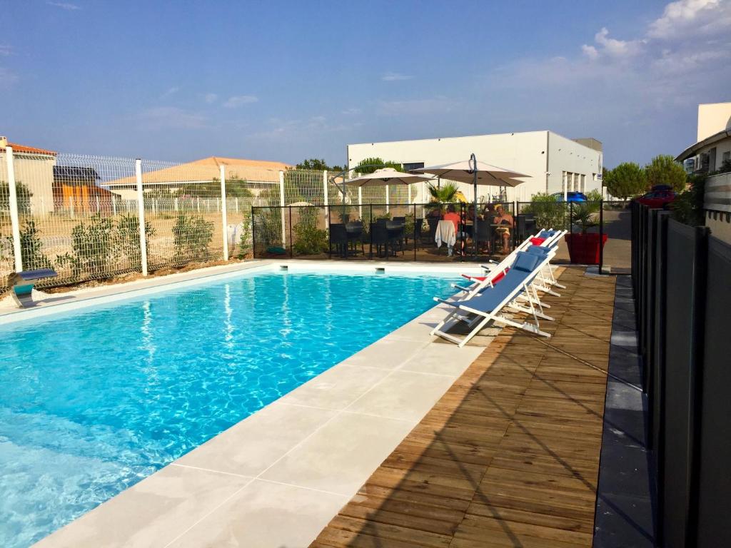 a swimming pool with lounge chairs next to a building at The Originals City, Hôtel Les Dômes, Perpignan Sud Saleilles in Perpignan