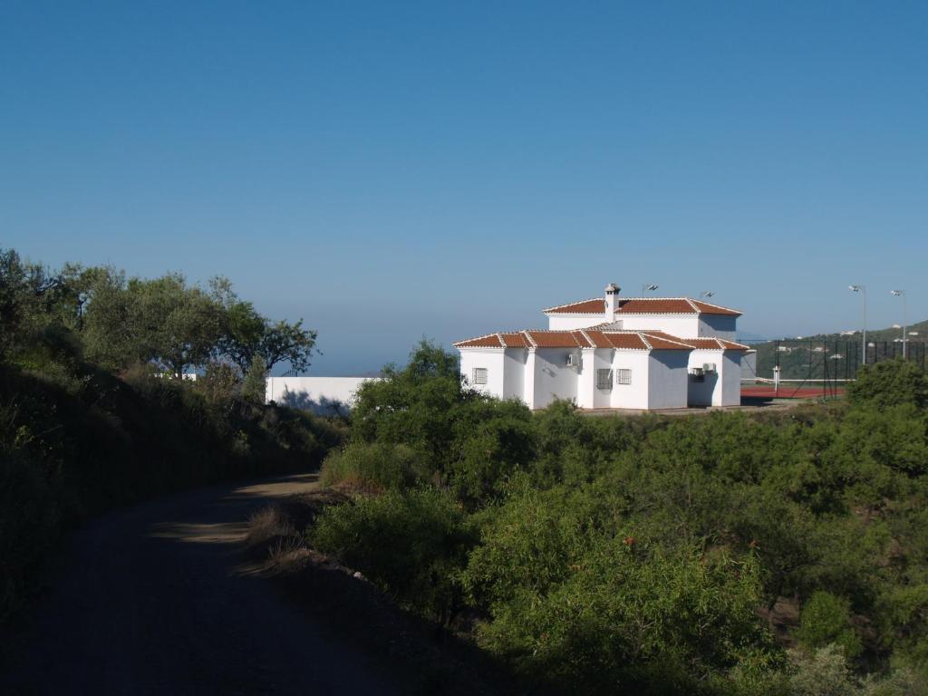 um edifício branco com um telhado no topo de uma estrada em casa Bandoleros em Arenas