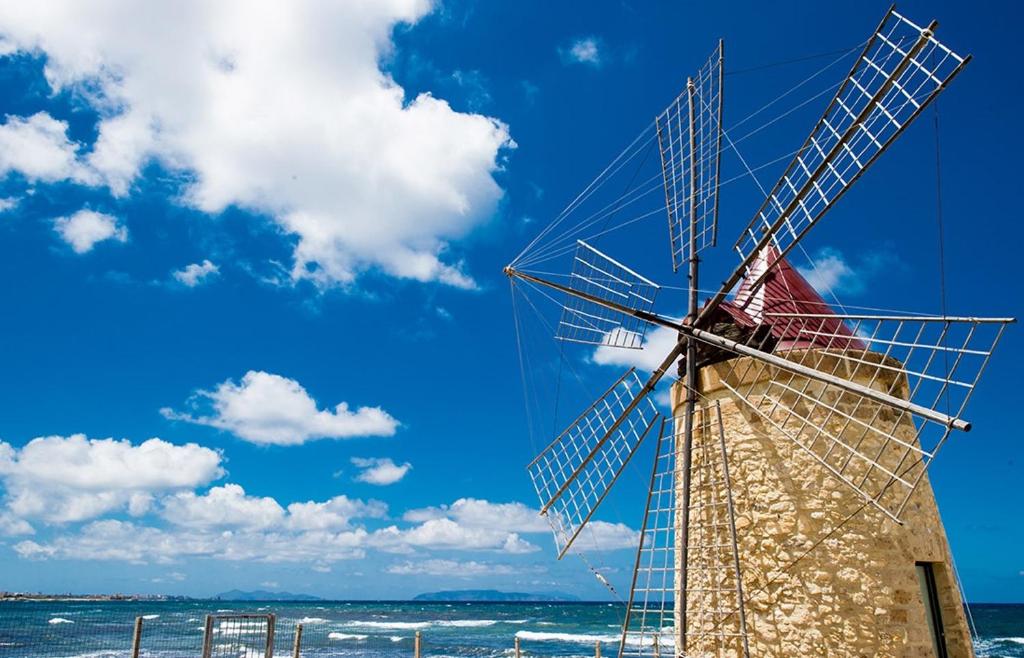 特拉帕尼的住宿－艾姆里尼度假酒店，海滩上的风车,背景是大海