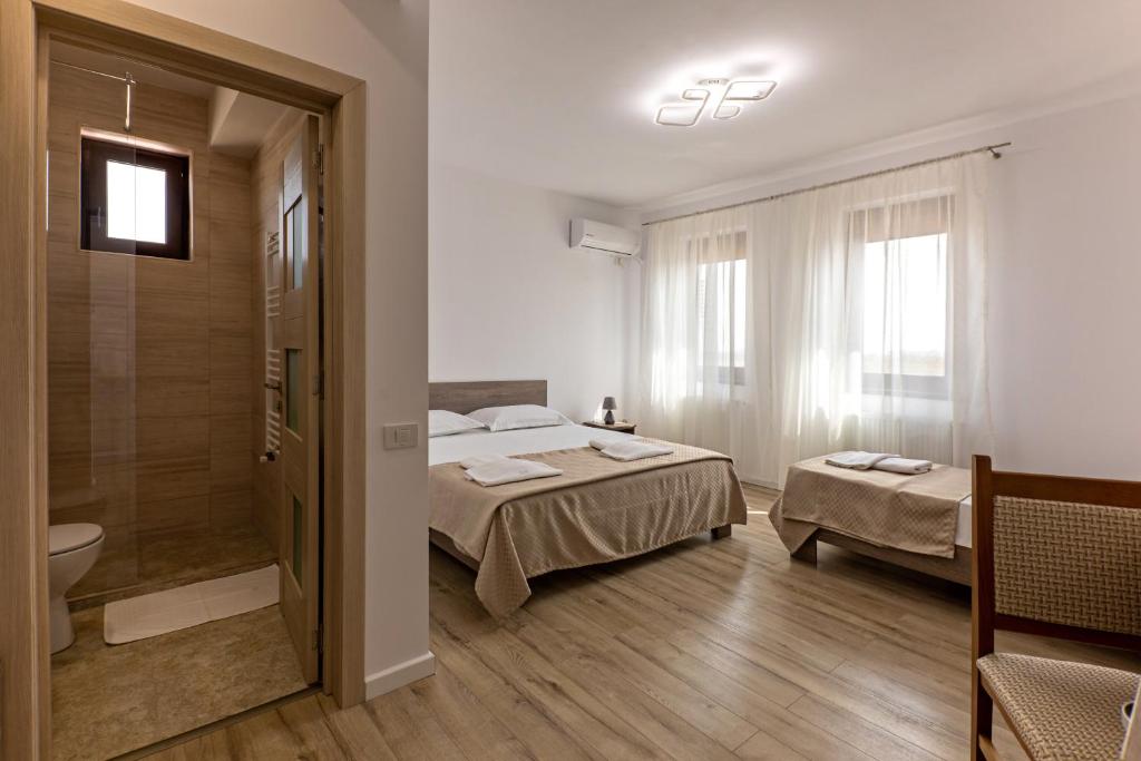 a room with two beds and a bathroom with a shower at Airport House in Otopeni