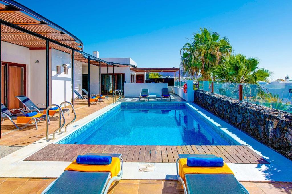 a swimming pool with two chairs and a house at Villa Corito in Playa Blanca