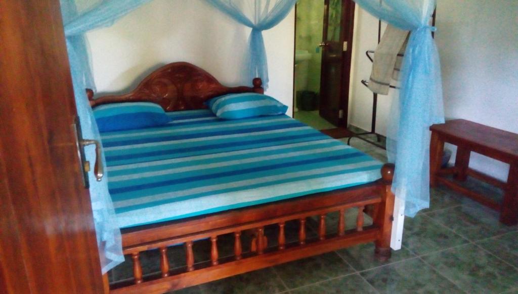 a bed with a wooden frame with blue pillows at Lagoon Inn in Hambantota