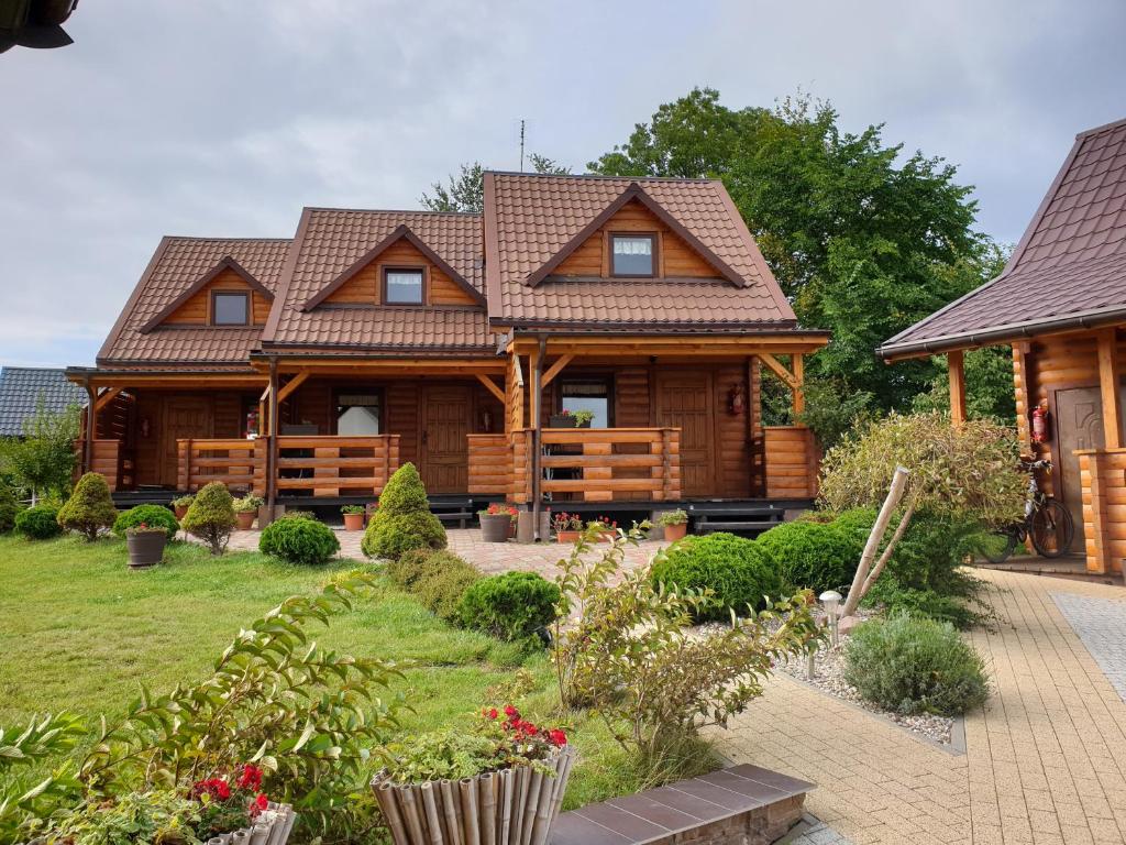 a log cabin with a garden in front of it at Domki letniskowe Sawinda in Rewal