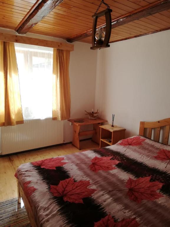 a bedroom with a bed and a table and a window at Rustic Rooms in Râşnov