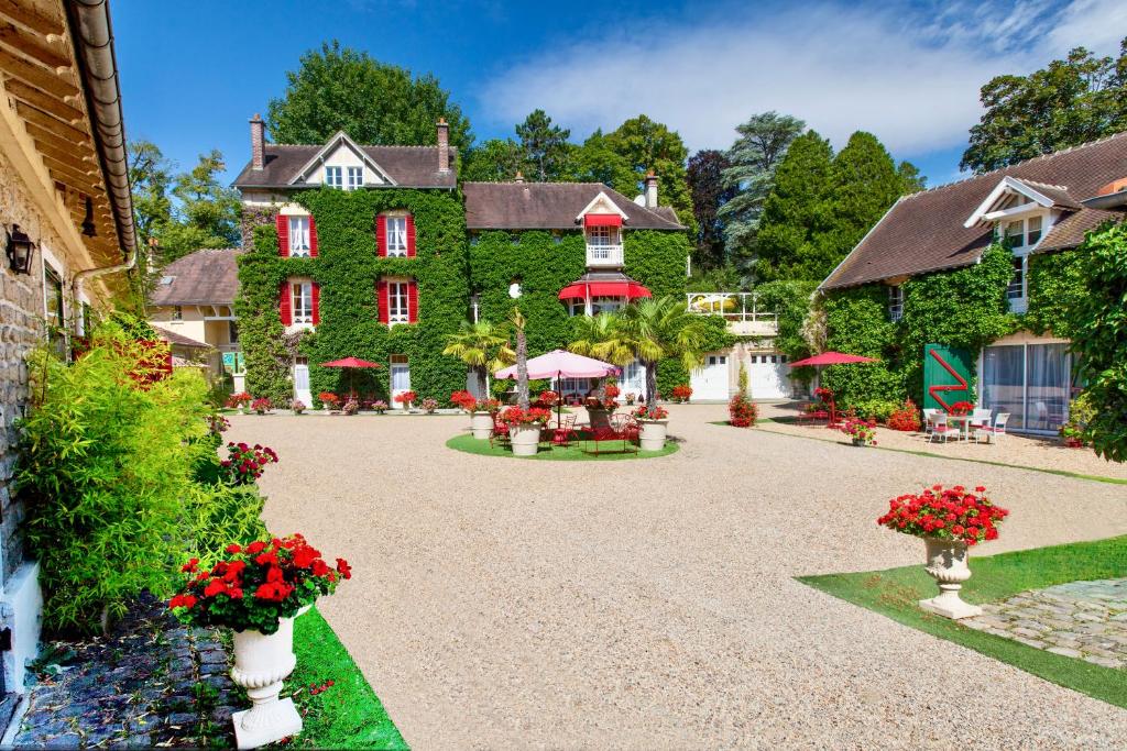 a large green building with red windows and flowers at Manoir des Cavaliers - BnB in Chantilly