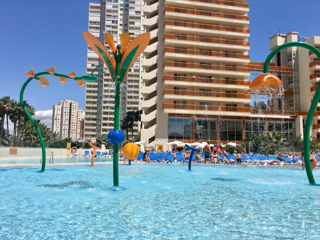 Una piscina con agua azul y postes verdes. en Hotel & SPA Dynastic en Benidorm