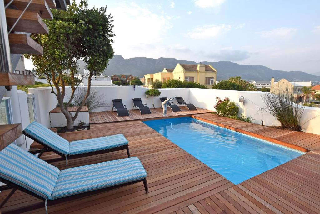 a patio with a swimming pool and deck with lounge chairs at Apartment Dolphin House in Hermanus