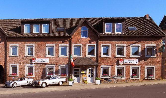 ein Backsteingebäude mit zwei davor geparkt in der Unterkunft Hotel Landhaus in Eschweiler