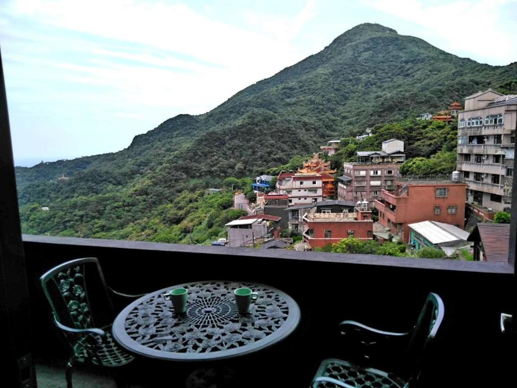 a table on a balcony with a view of a mountain at Night Sea Homestay in Jiufen