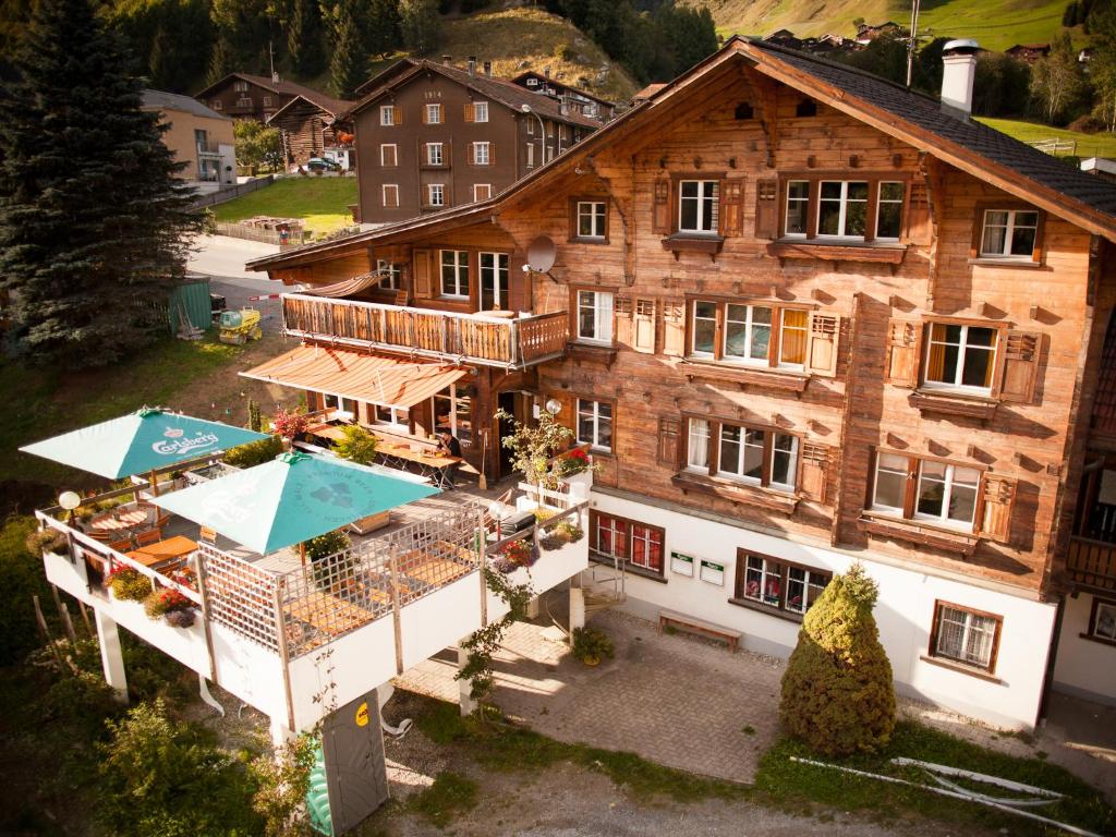 an aerial view of a large wooden building with umbrellas at Nangijala Hostel in Disentis