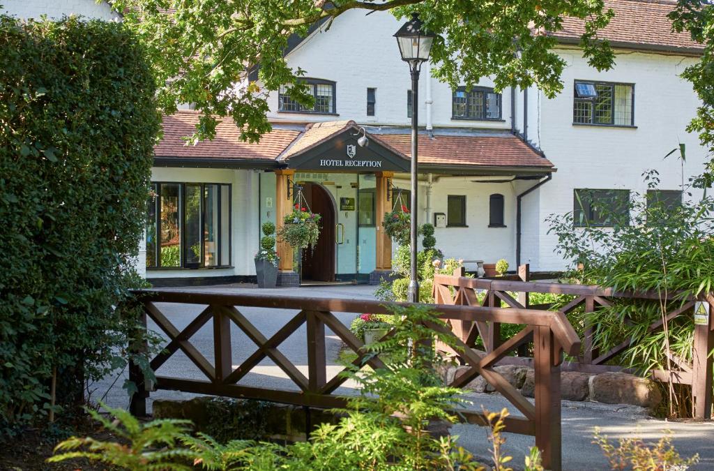 a house with a wooden fence in front of it at Macdonald Craxton Wood Hotel & Spa in Ledsham