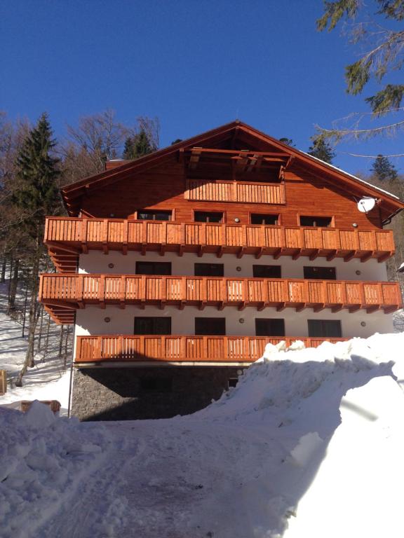 a large wooden building with a bridge in the snow at Apartmánový dom Poludnica I., Chopok Juh, Jasná in Tale