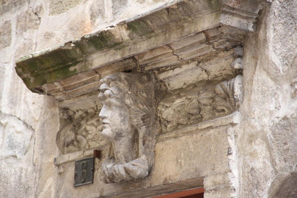 a stone sculpture of a face on the side of a building at Logis du Cagaïre in Le Puy en Velay